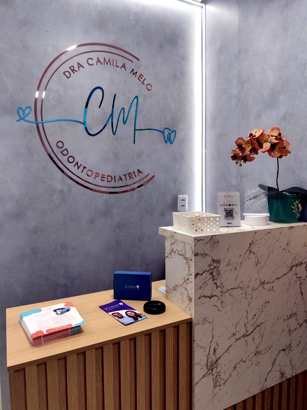 Recepção da clínica com a logo da Dra. Camila Melo